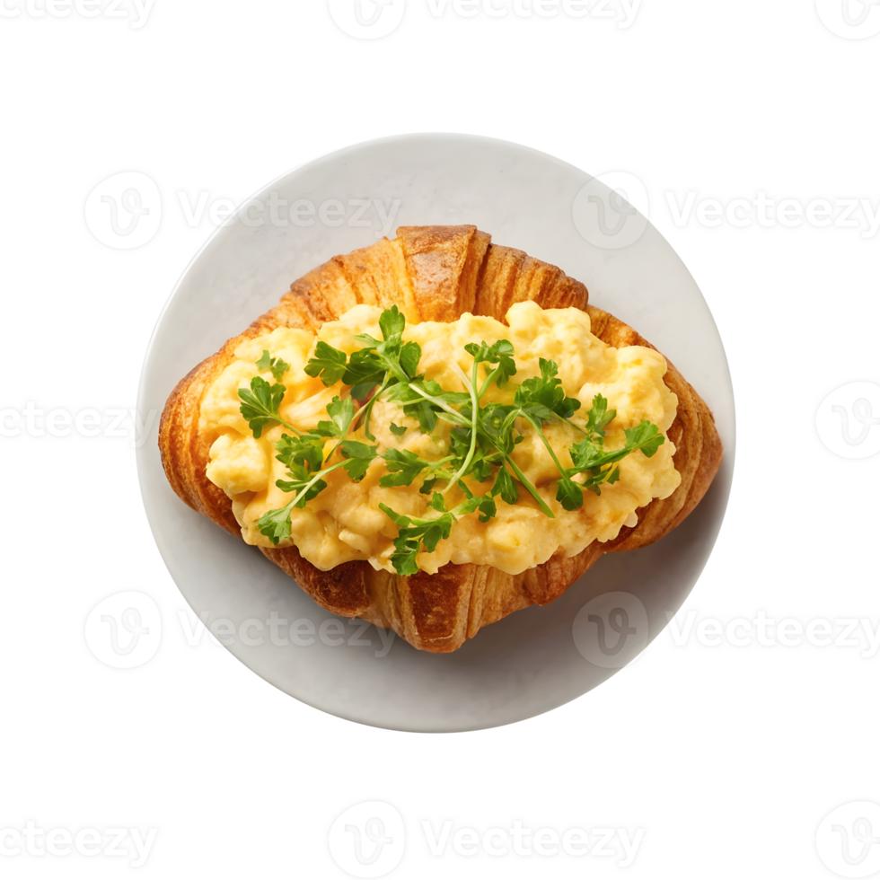 Delicious croissant topped with fluffy scrambled eggs and fresh herbs served on a plate png