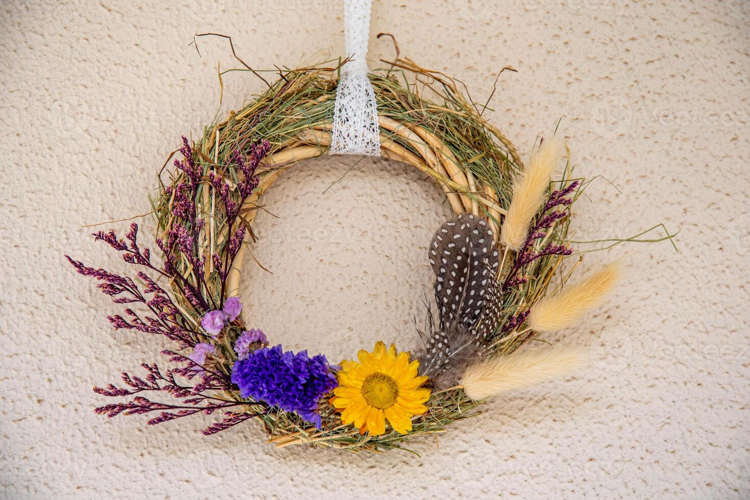 Handmade wreath crafted from dried flowers and herbs showcasing vibrant sunflowers, lavender, and delicate feathers, perfect for unique home decoration photo