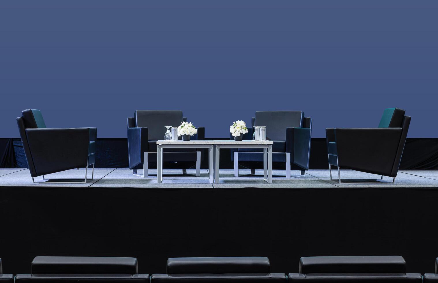 Four black armchair for speaker on stage and blue screen display backdrop at business presentation exhibition photo
