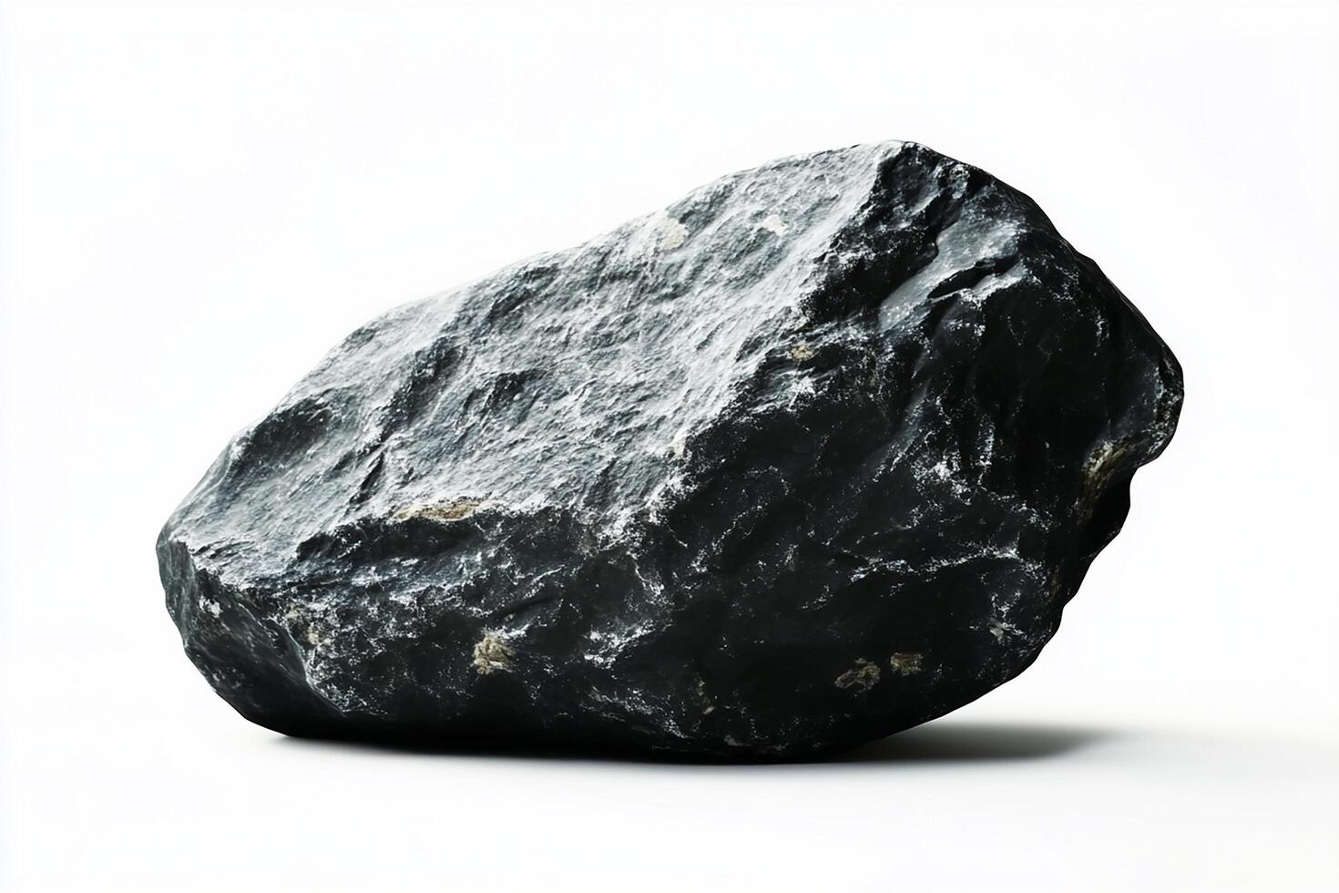 A single dark gray rock with rough texture on a white background in a studio setting view photo