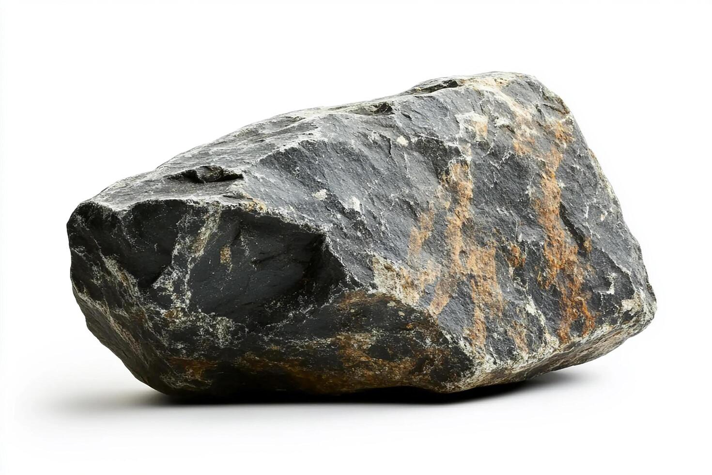 A large dark gray rock with brown streaks sitting on a white surface in a studio shot photo