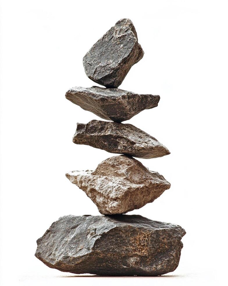 A stack of five gray rocks balanced on top of each other against a white background studio shot photo
