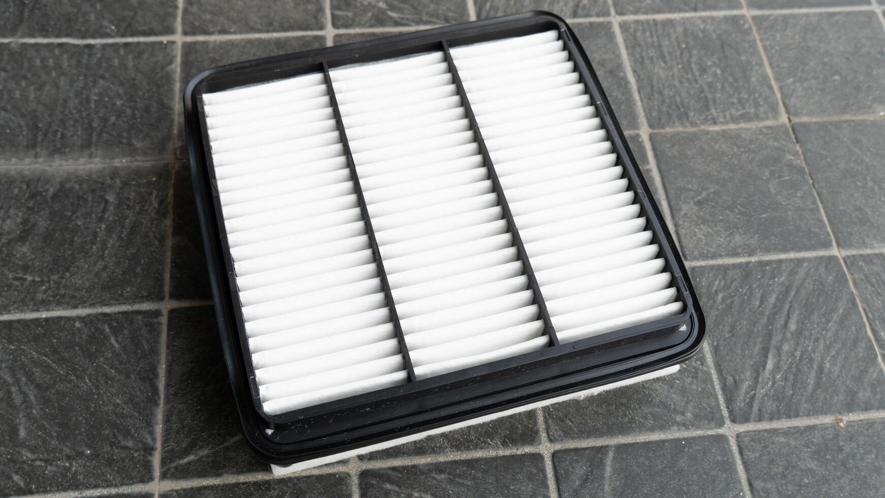 Top view of new engine air filter of car. Cloth panels are covered with clean white. Placed on a black tiled floor. photo