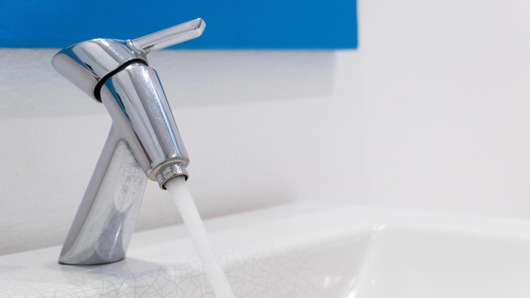 Taps that are turned on. Clean water flowing out of the faucet. A beautiful and clean bathroom sink. photo