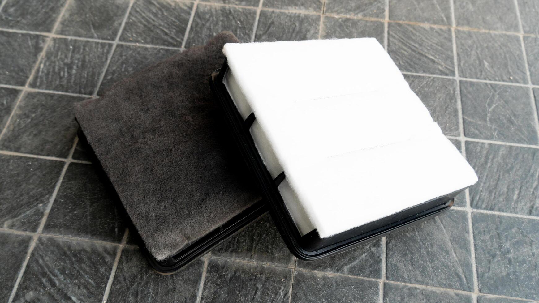 Old and new filters are stacked clearly on top of each other. Placed on a black tiled floor. photo