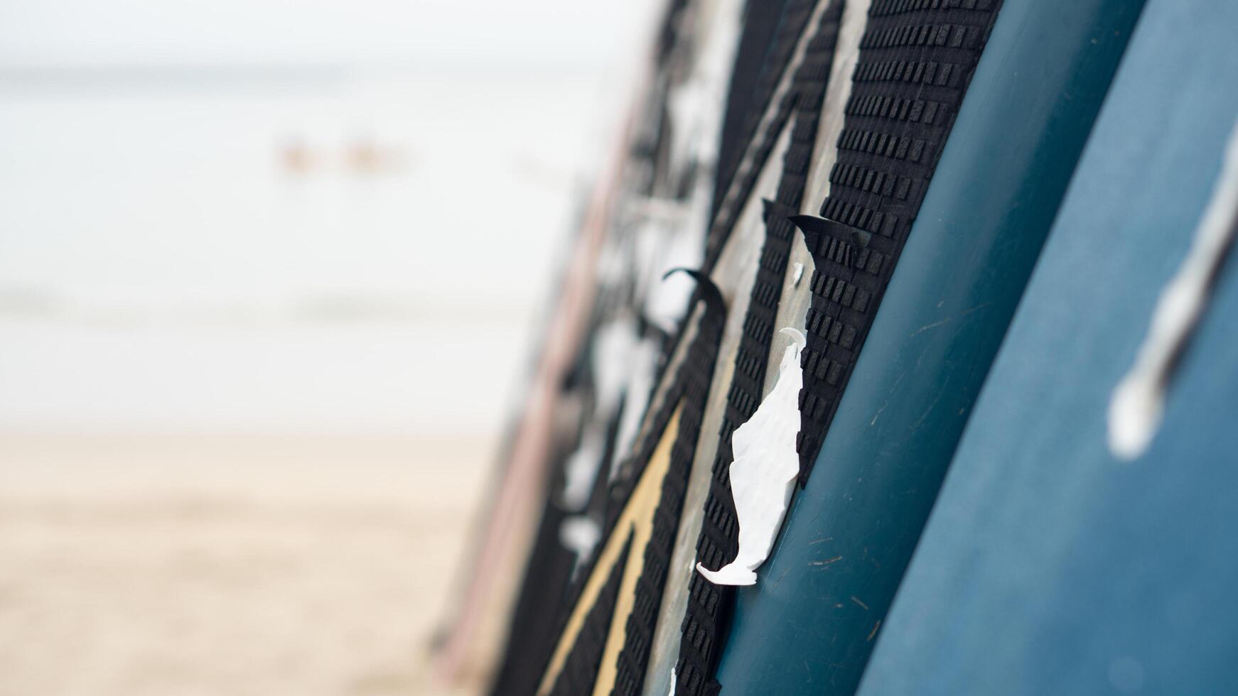 Abstract background of old surfboard. Leaning against the blurry beach and showing bright sunlight. photo