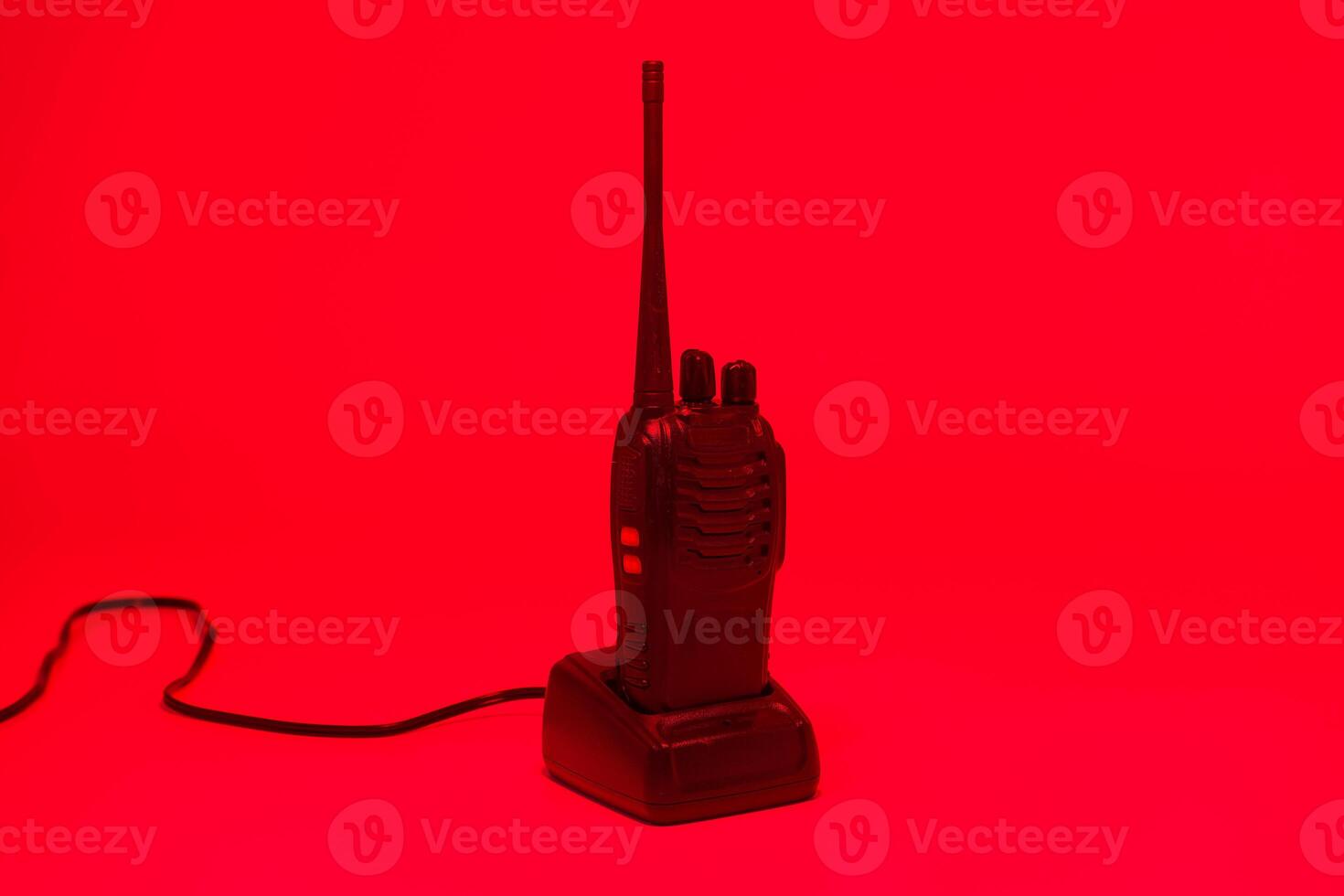 Vintage walkie talkie on charger against a bright red background, showcasing retro design and technology from the past century photo