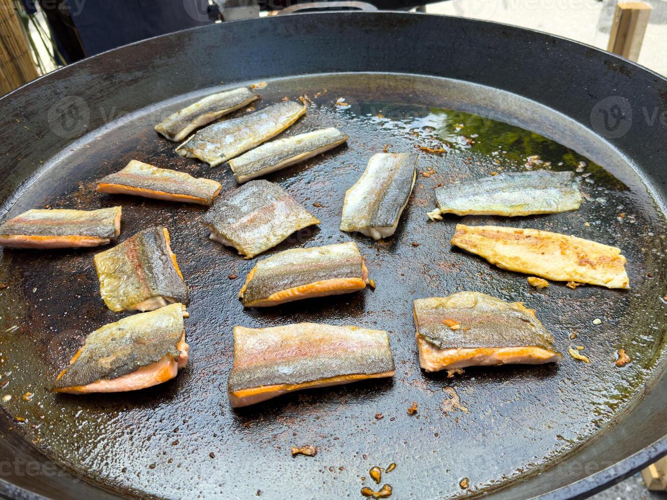 Grilled salmon skins sizzling on large outdoor pan photo