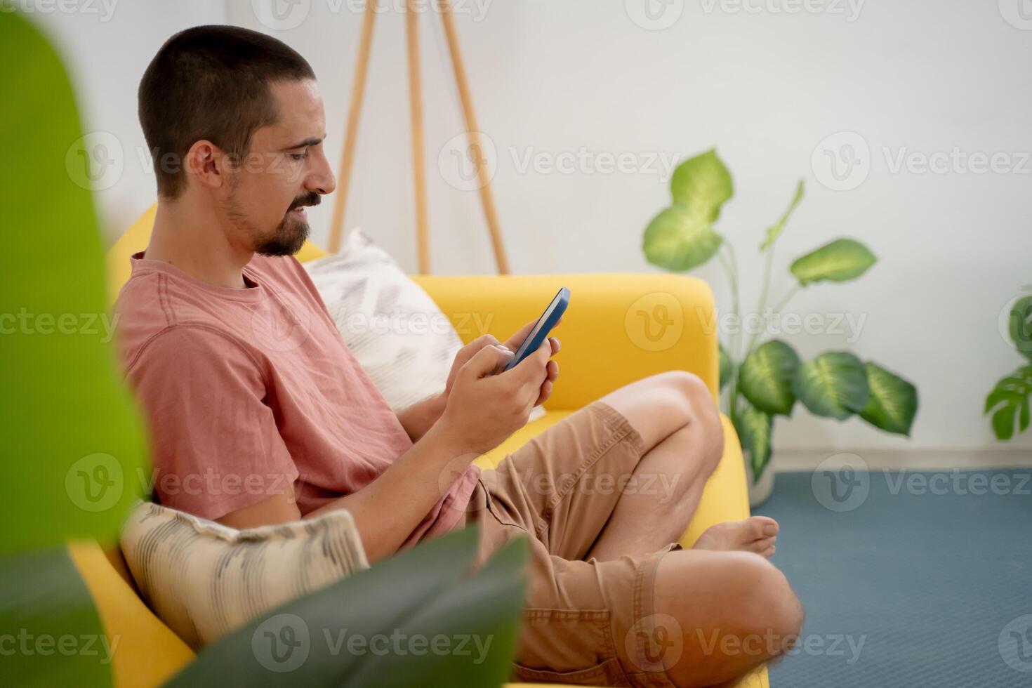 A Man Comfortably Relaxing on a Couch While Using His Smartphone in a Cozy Living Room photo