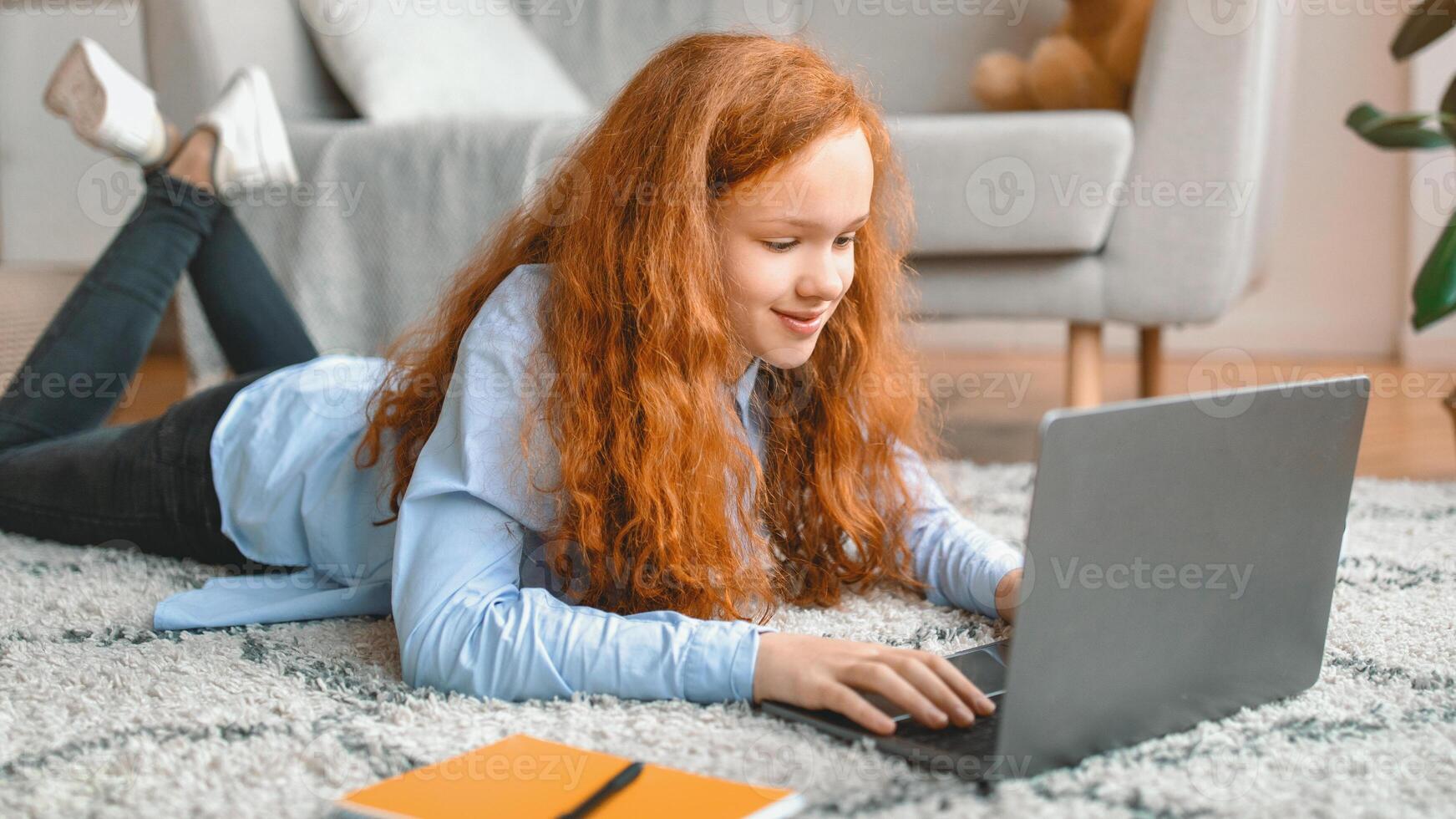 Girl using laptop while lying on rug photo