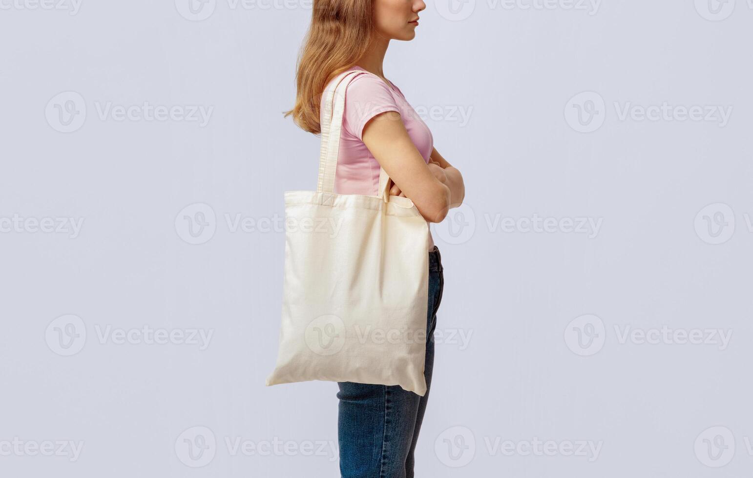 Side View Shot Of Young Woman Carrying Blank Eco Tote Canvas Bag, Unrecognizable Millennial Lady Enjoying Sustainable Shopping, Standing Over Light Studio Background, Cropped Image, Copy Space photo