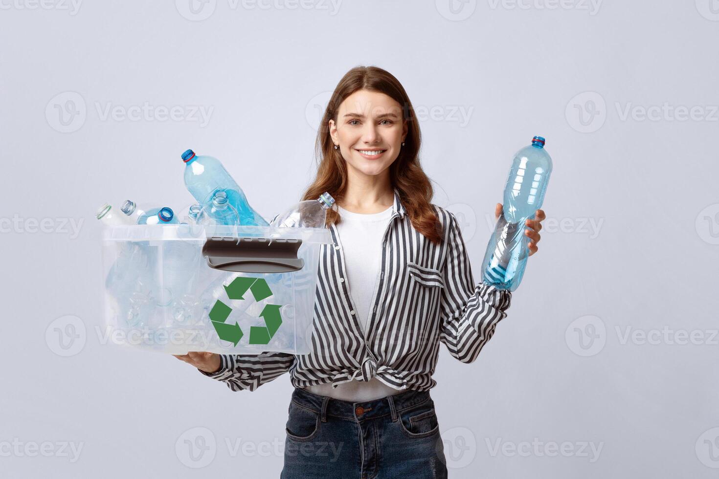 Waste Sorting. Smiling Eco Volunteer Woman Holding Container With Empty Plastic Bottles, Cheerful Lady Promoting Garbage Recycling Concept While Posing Over Gray Studio Background, Free Space photo