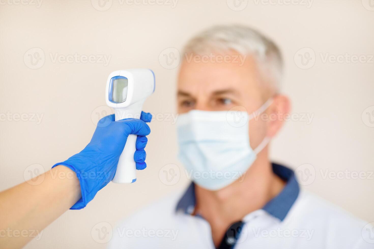 Doctor hand measuring mature man's temperature with digital thermometer before vaccination against covid-19, selective focus. Copy space. Antiviral population protection, coronavirus immunization photo