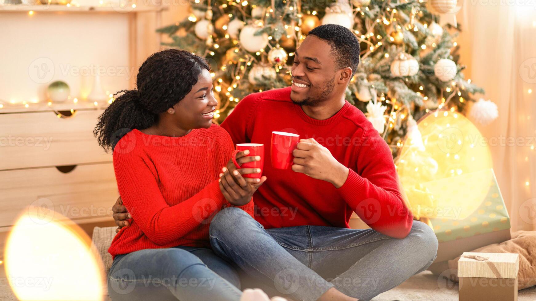 Couple sharing drinks by Christmas tree photo