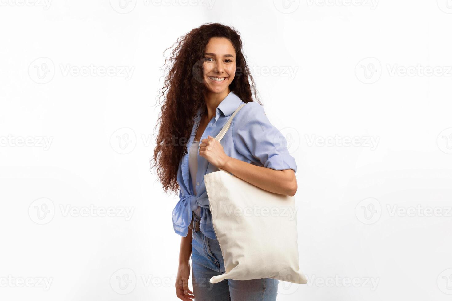 Cheerful Woman With White Eco Bag Smiling To Camera Posing Standing Over White Studio Background. Female Consumer Carrying Flax Tote Shopper Handbag. Eco-Friendly Lifestyle, Stop Using Plastic Concept photo