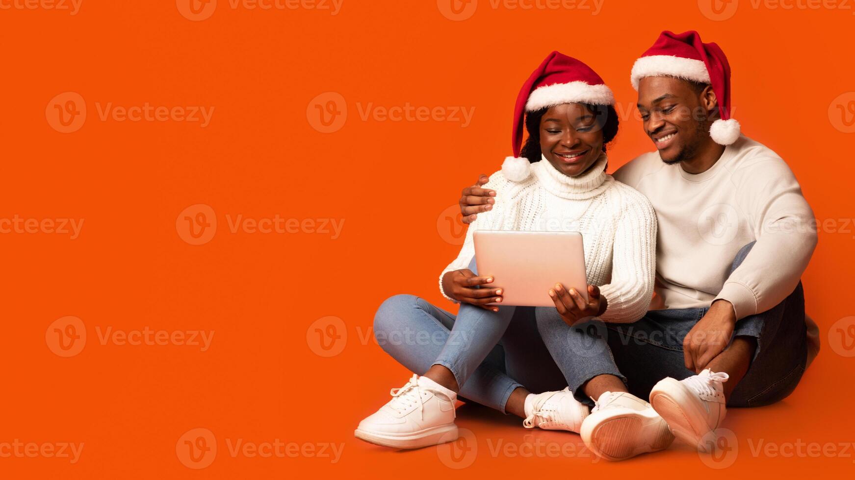 Couple with Christmas hats using tablet photo