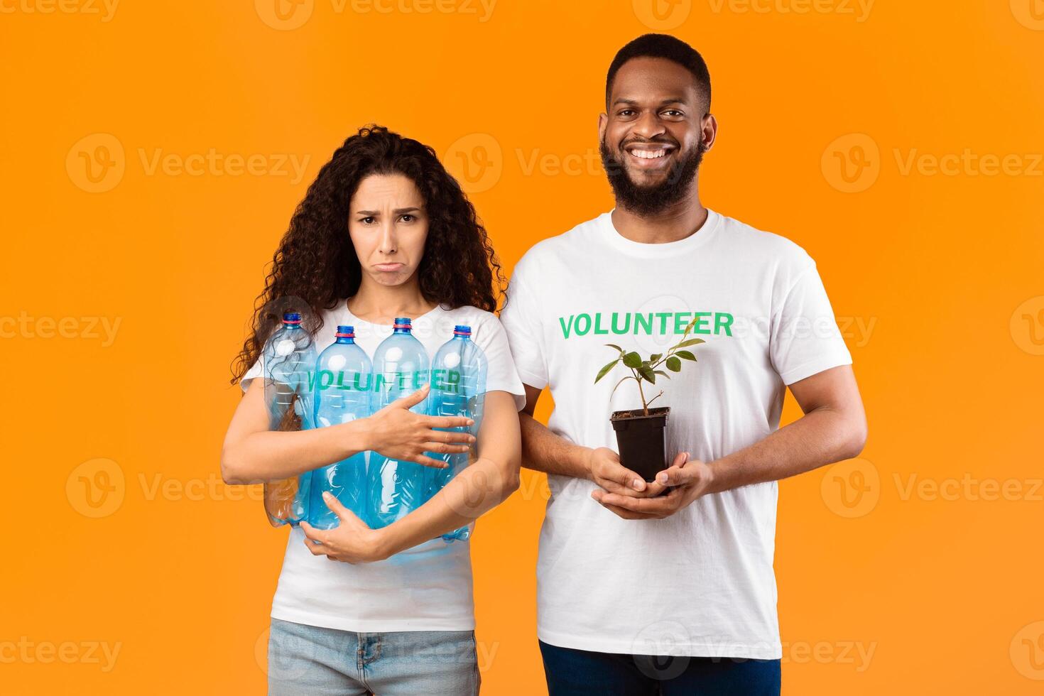 Don't Litter And Care For Nature. Two Volunteers Holding Plant In A Pot And Used Plastic Bottles Standing Over Yellow Studio Background. Ecology, Protection Of Environment Concept photo