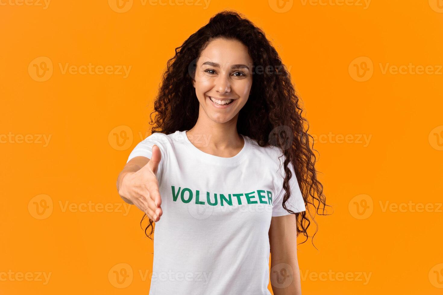 Cheerful Volunteer Woman Offering Hand For Handshake Greeting To Camera Posing Standing Over Yellow Studio Background. Volunteering, Voluntary Work, Join Our Team Concept photo