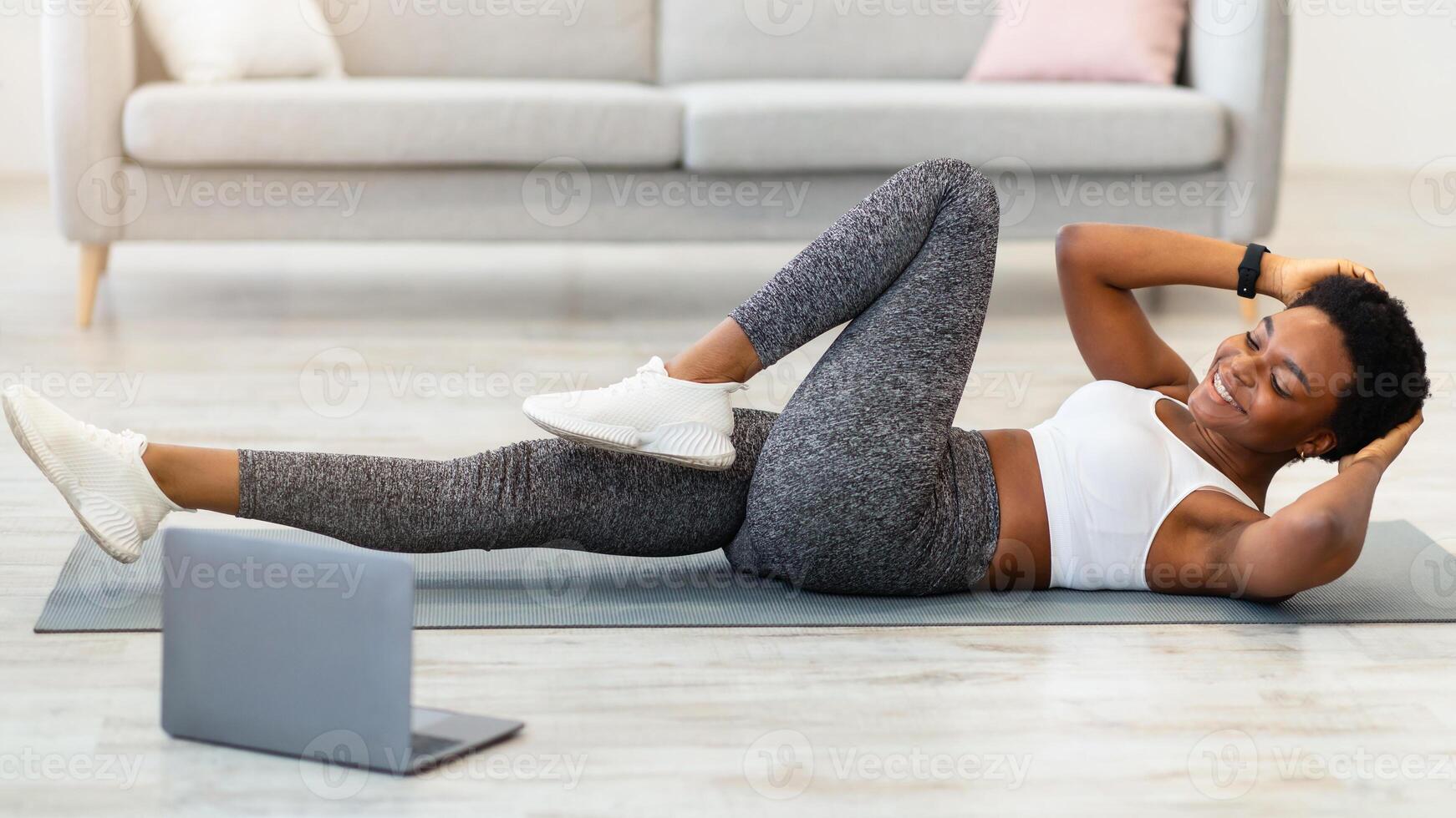 Woman exercising at home with laptop photo