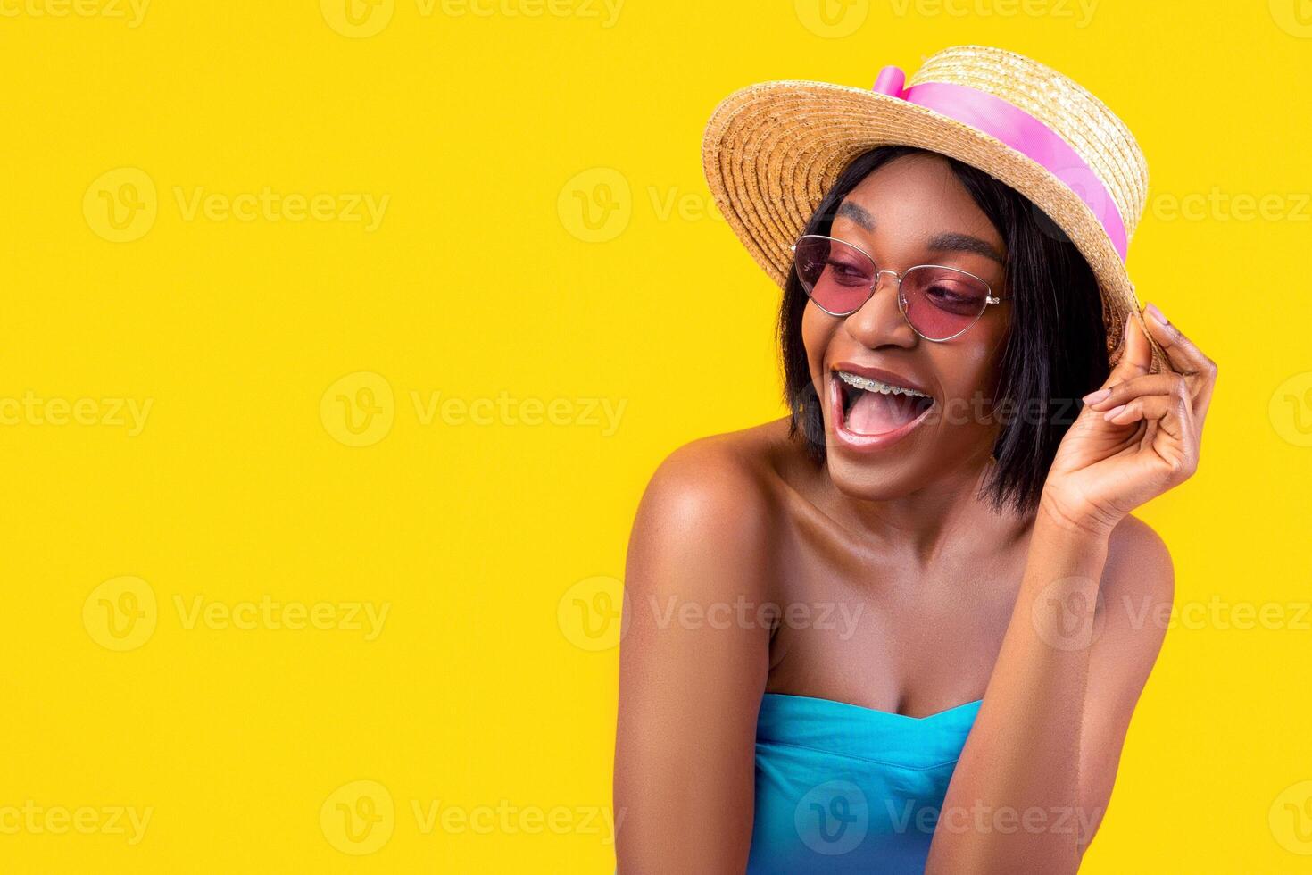 Flirty young black woman in summertime outfit opening mouth in excitement, posing on orange studio background. Playful African American lady looking forward to summer vacation photo