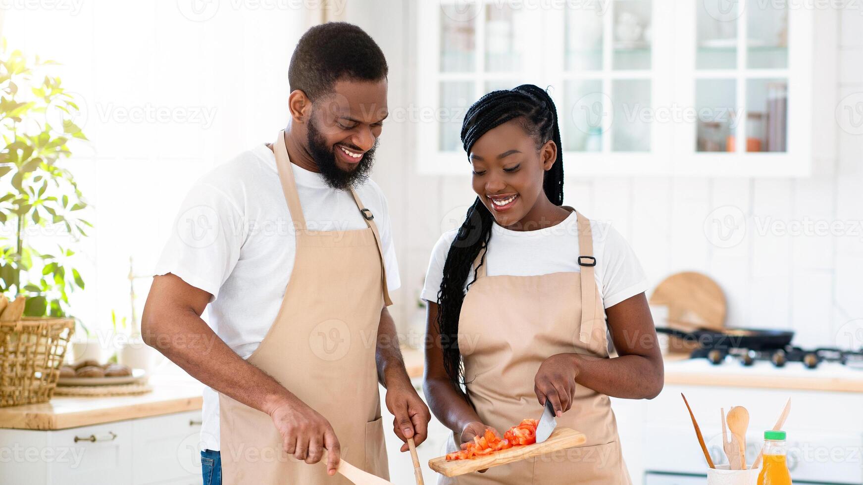 Vegan Diet. Happy young black couple cooking fresh vegetable salad together in kitchen, millennial african american spouses enjoying preparing healthy food and spending time at home, copy space photo