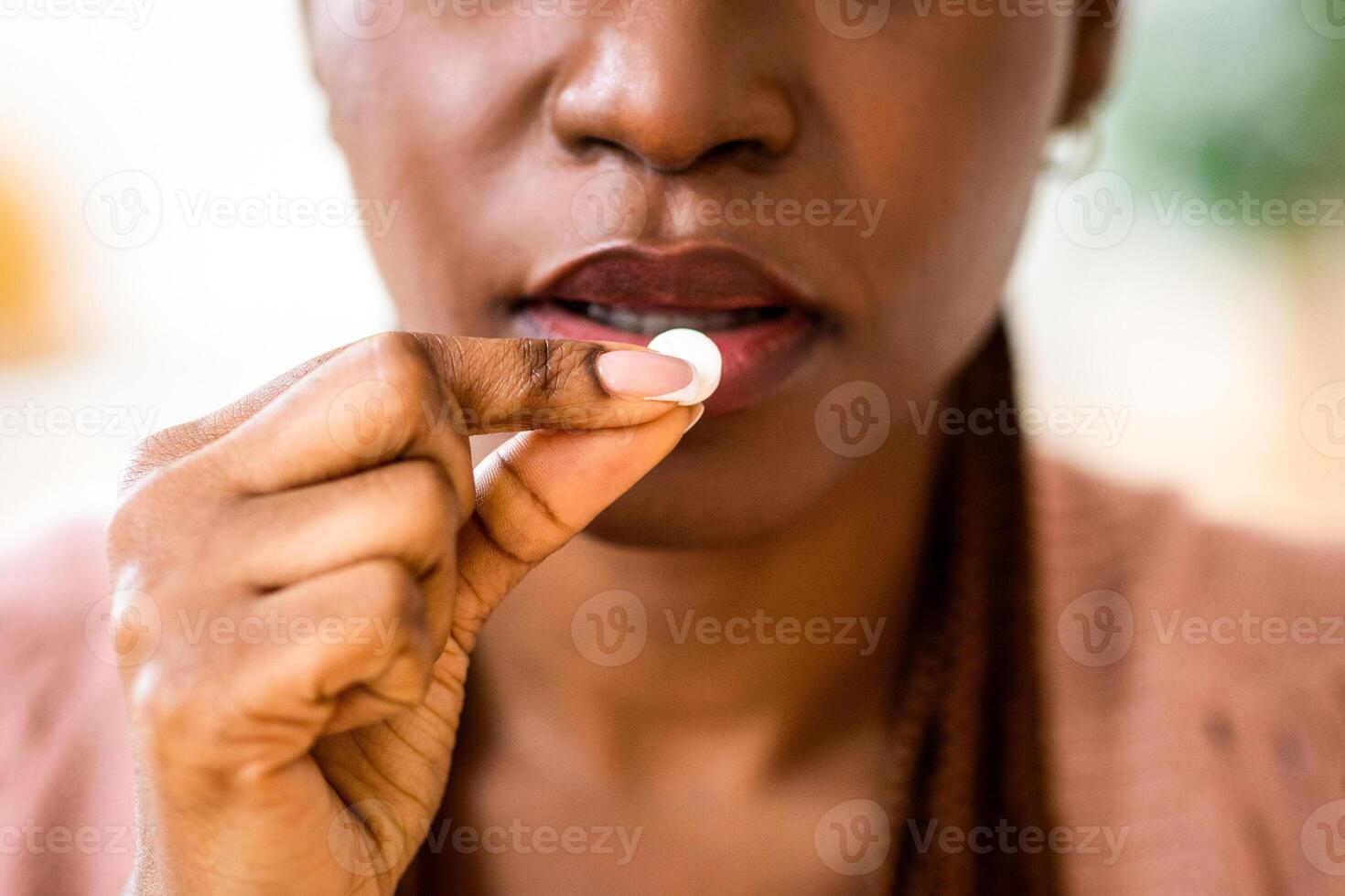 Unrecognizable Black Lady Taking Medicine At Home, Eating Beauty Supplement Pill, Unrecognizable African American Female Having White Medication Drug For Pain Relief, Cropped Image, Closeup Shot photo