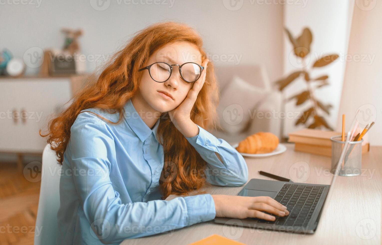 Boredom Concept. Teenage girl wearing eyeglasses sleeping while sitting at table, resting head on hand, tired of school, studying and reading. Female pupil feeling exhausted, doing homework, learning photo