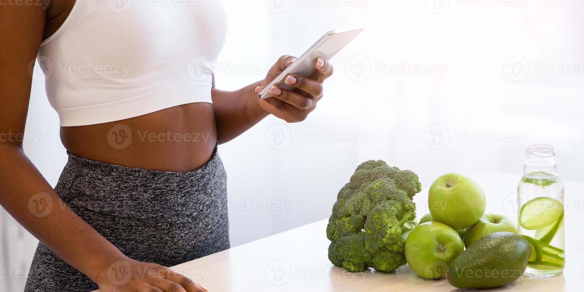Dieting Application. Black Woman Using Phone Losing Weight Standing In Modern Kitchen At Home. Detox Recipes For Slimming, Healthy Eating And Weight Loss App Concept. Cropped photo