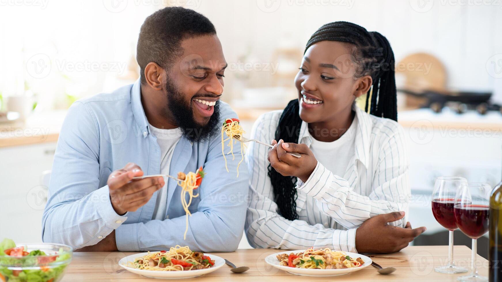 Joyful Black Spouses Having Lunch At Home, Eating Spaghetti And Drinking Wine. Romantic African American Couple Tasting Delicious Food And Enjoying Spending Time At Home Together, Closeup photo