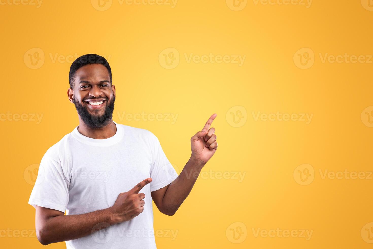 Look There. Cheerful African American Man Pointing Fingers Aside Showing Copy Space Posing Standing Over Yellow Studio Background, Smiling To Camera. Great Offer Advertisement Concept. photo