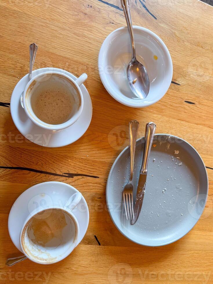 Empty Coffee Cups and Used Dishes on Wooden Table photo