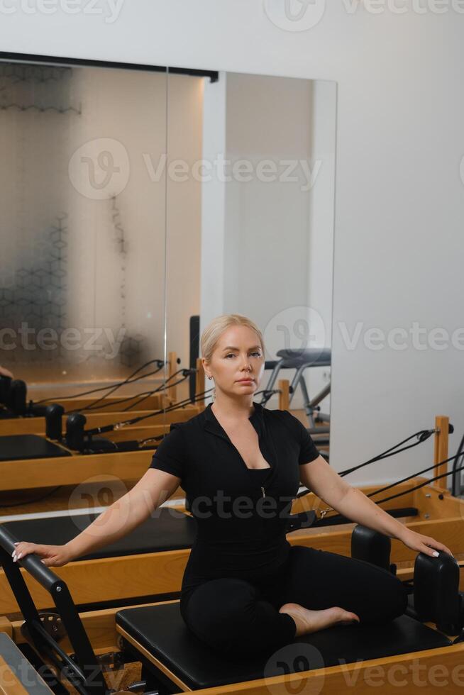 Pilates class in a modern studio with a focused instructor demonstrating an exercise during a morning session photo