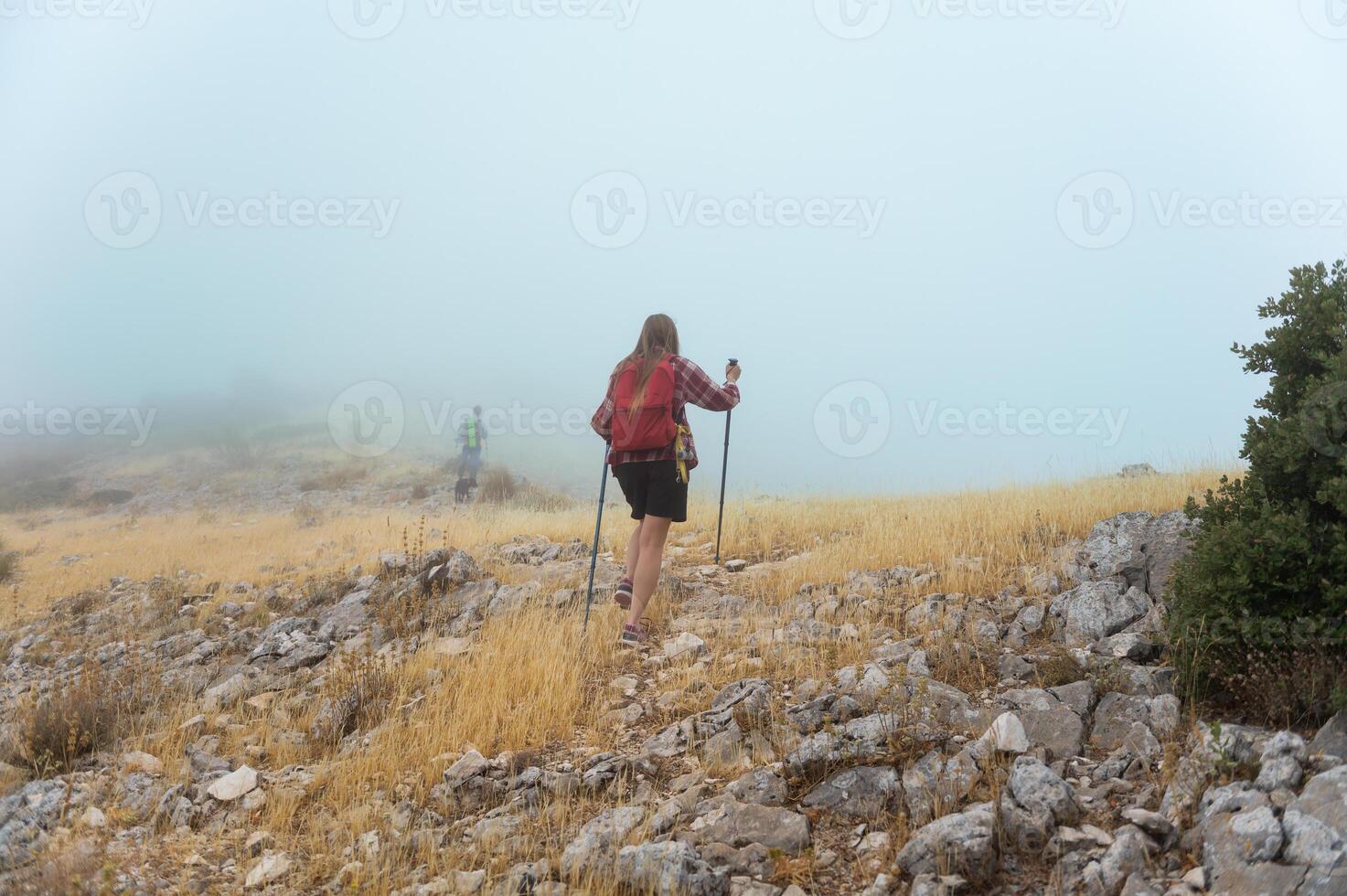 Hikers Exploring a Rocky Fog-Covered Mountain in the Morning Mist photo