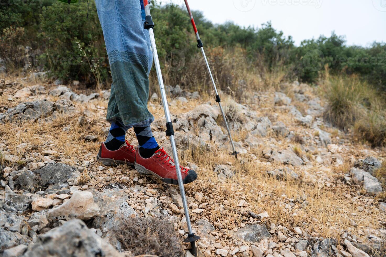 Exploration in Rocky Terrain. Hiker Trekking with Poles and Durable Shoes photo