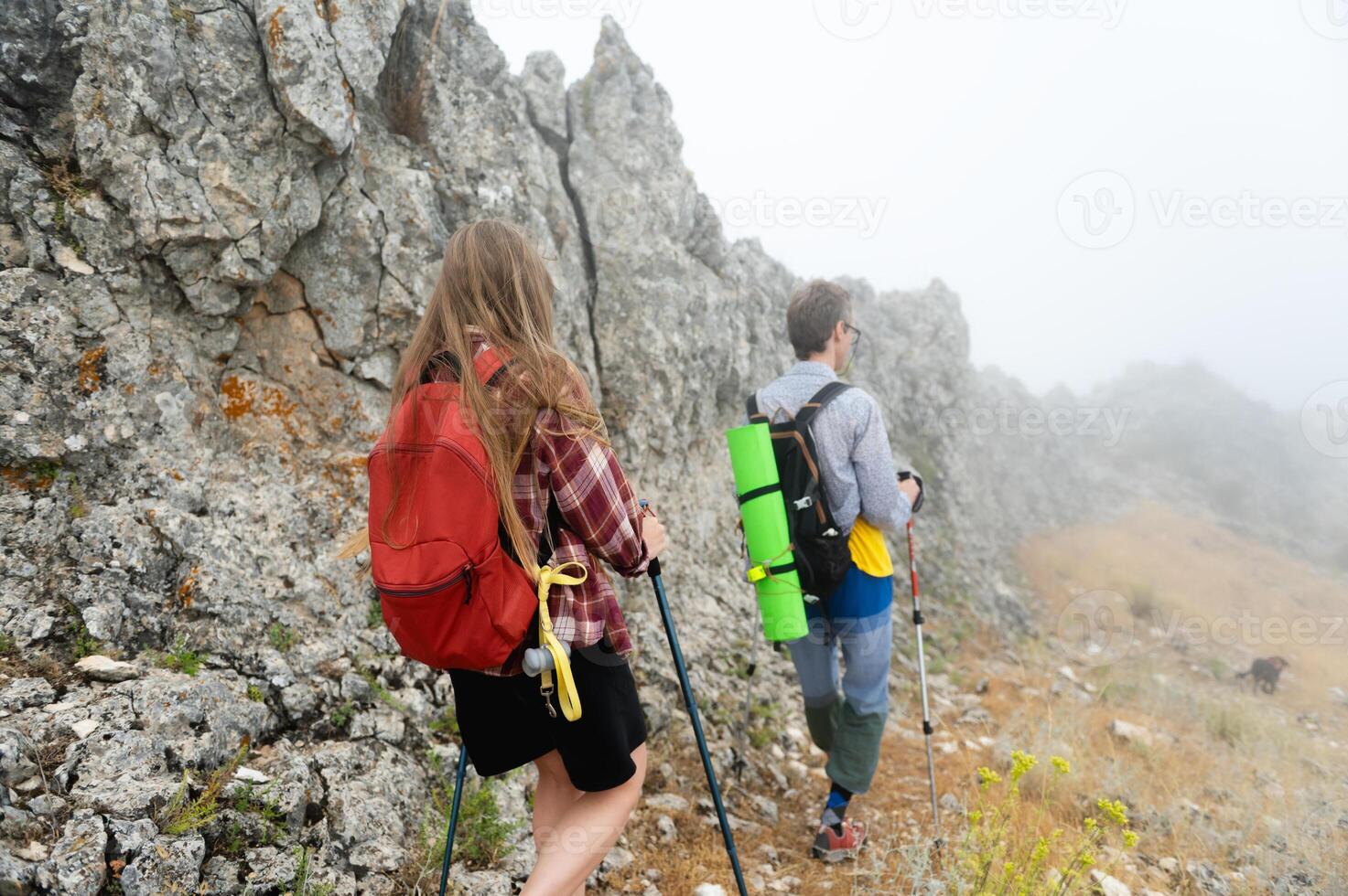 Hikers Exploring Foggy Mountain Trails with Backpacks and Trekking Poles photo