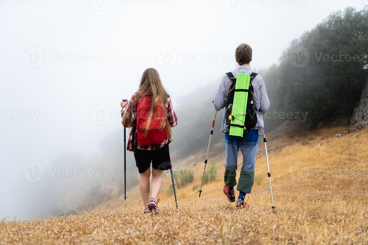 Two Hikers Navigating Through a Foggy Landscape in the Early Morning photo
