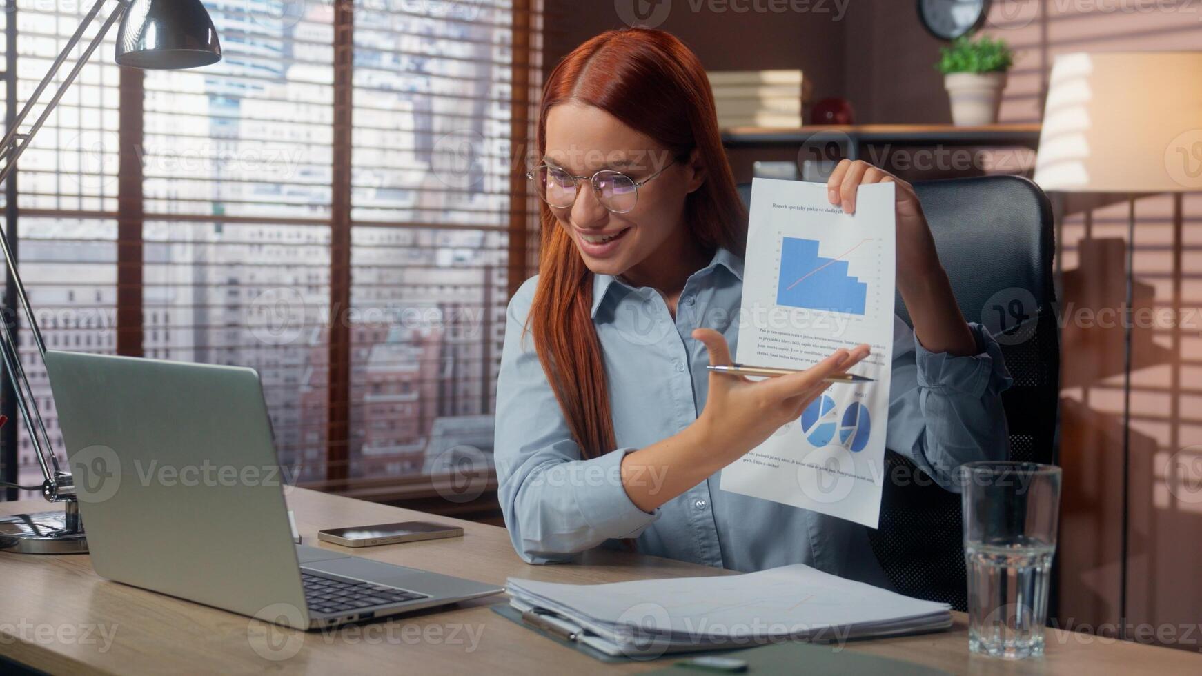 Caucasian businesswoman smiling happy talking call laptop in office showing good results financial grows graphic data marketing success business woman girl female at table virtual consultation photo