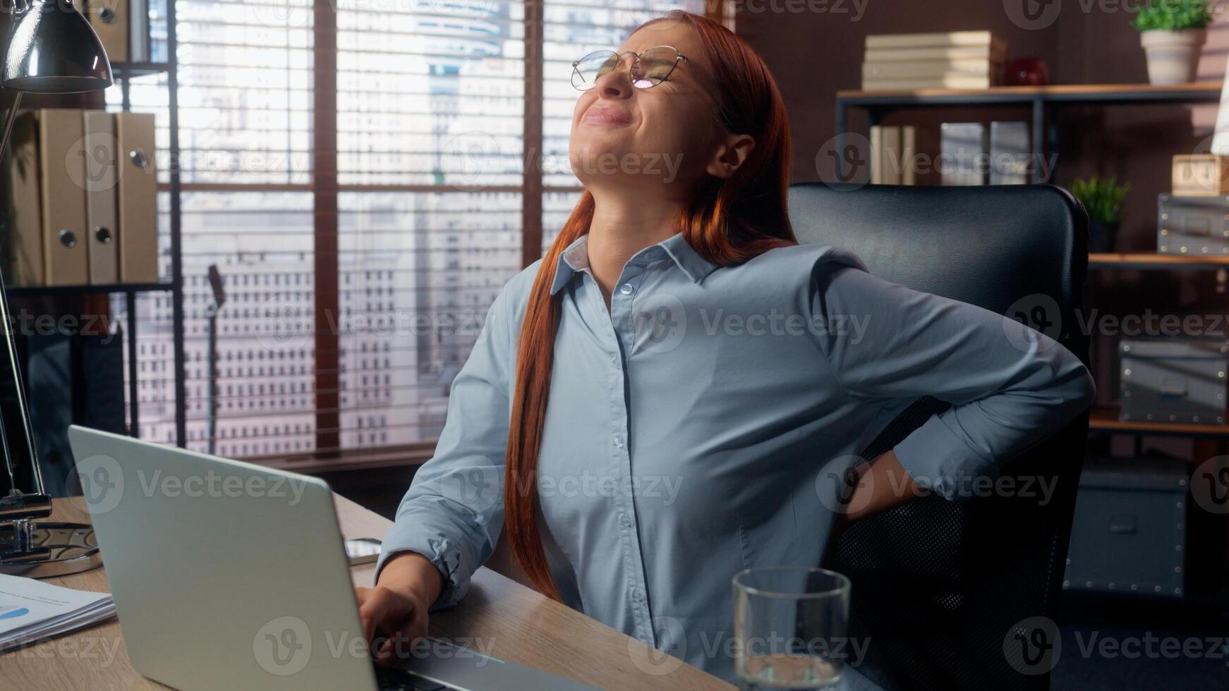 Caucasian business woman in office typing laptop feeling back spine ache pain tired overworked ill sick uncomfortable position backache sitting businesswoman female girl working suffer health problem photo