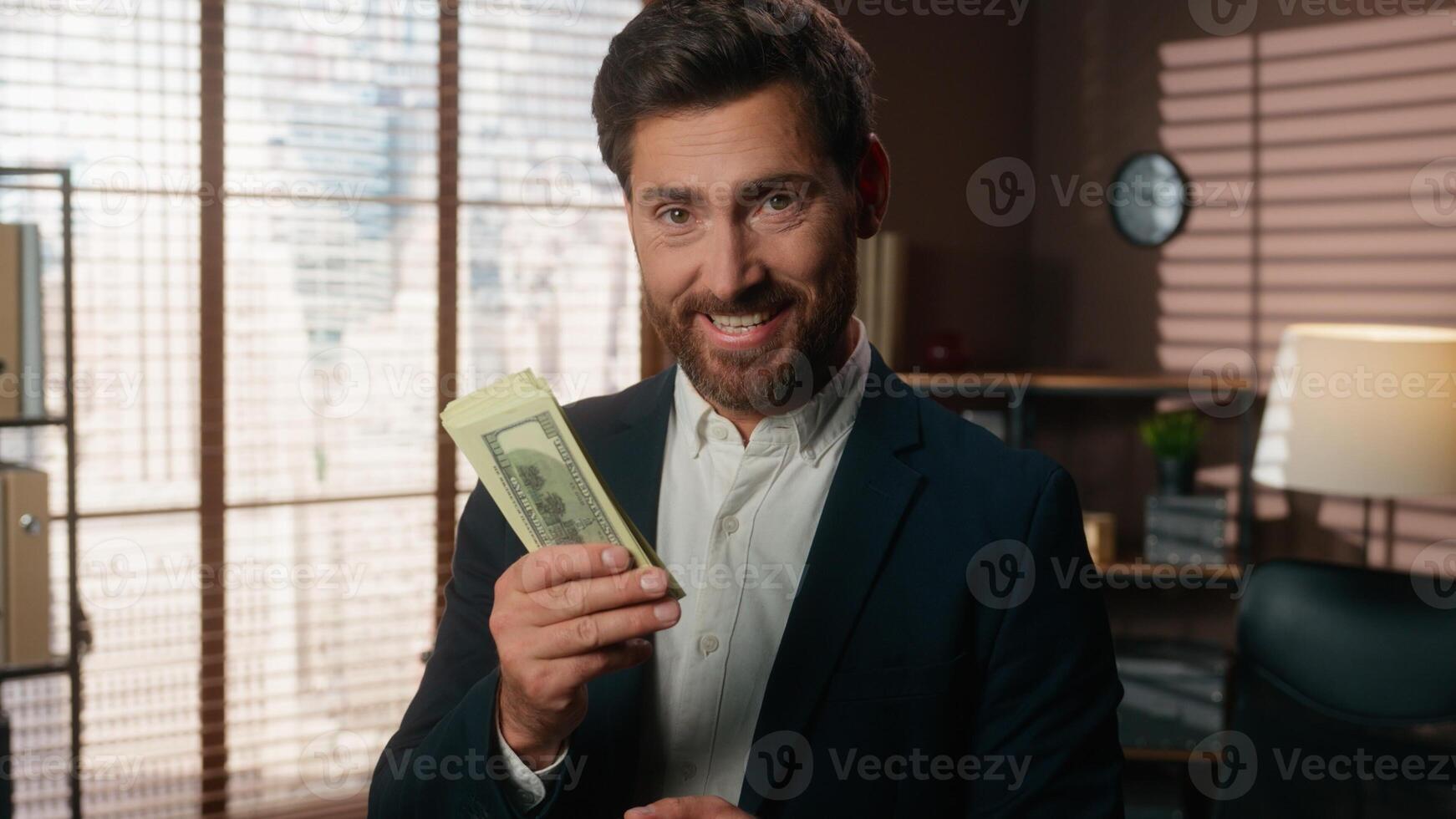 Caucasian middle-aged businessman male business man holding money sniffing smell aroma of cash happy rejoice job financial success smiling at camera in office finance achieve employer hold dollars photo