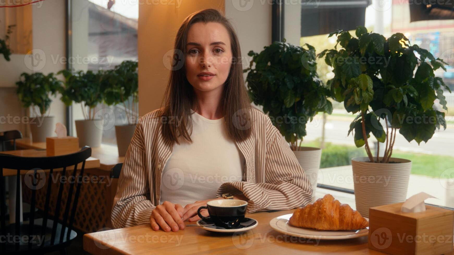 Caucasian woman visitor in cafe business lady calm relaxed girl female at cafeteria table relaxing with coffee and croissant looking at camera portrait customer order service enjoying coffeehouse photo