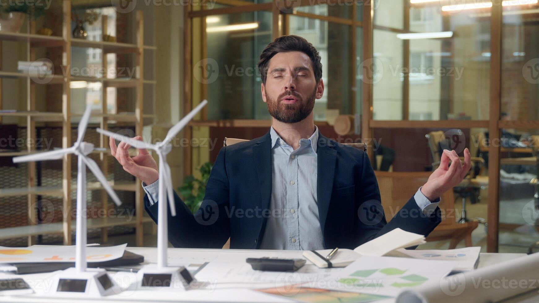 Engineer meditating business wind turbine project models stress relief green startup renewable energy design focus Caucasian man male peaceful businessman mindfulness sustainable innovation at office photo