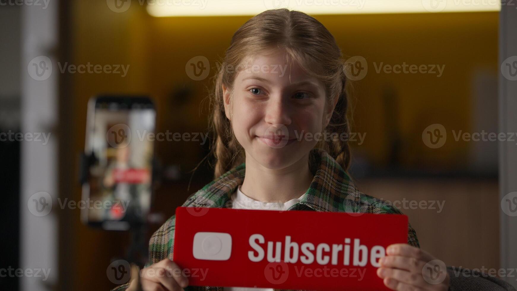 Happy little girl blogger filming blog showing thumbs up subscribe sign button at home cheerful Caucasian child kid gesturing influencer recording vlog mobile phone camera tripod like recommend photo