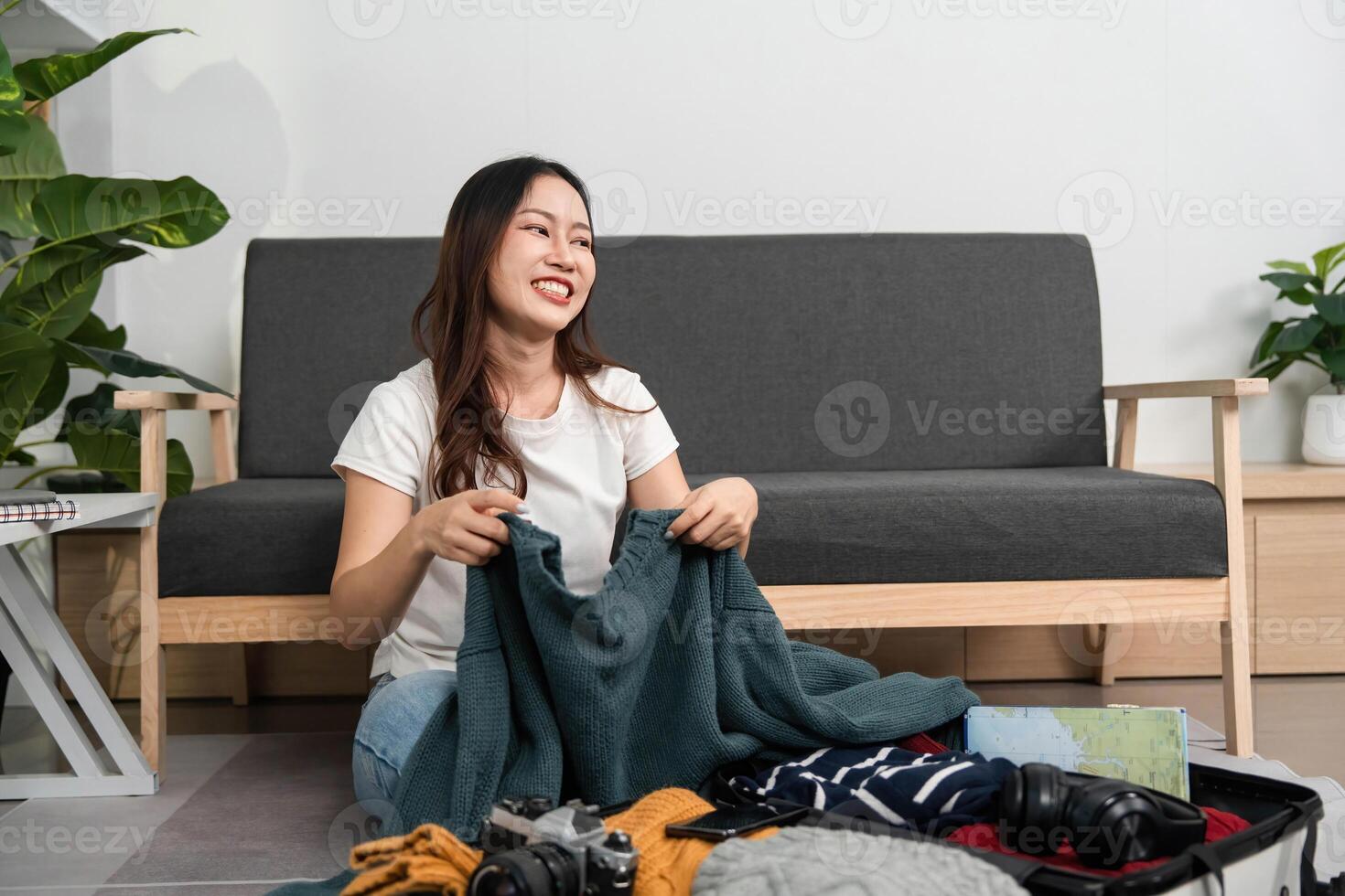 Packing for Travel. Young woman organizing clothes and accessories in a suitcase. photo