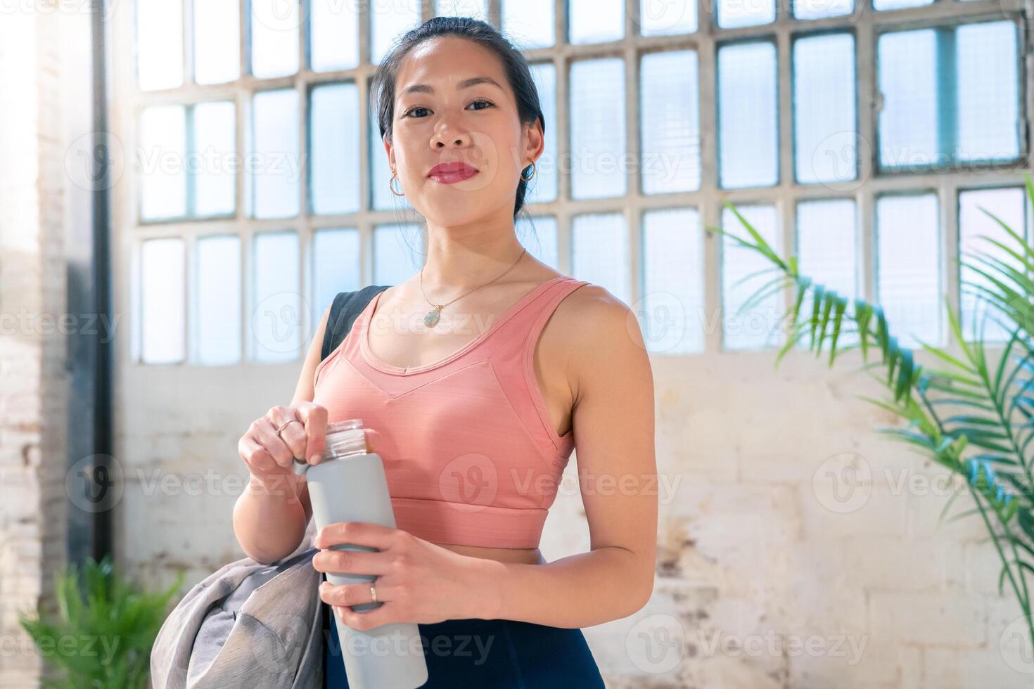 Confident Young Woman Dressed in Athletic Wear Holding a Water Bottle Ready for Active Lifestyle photo