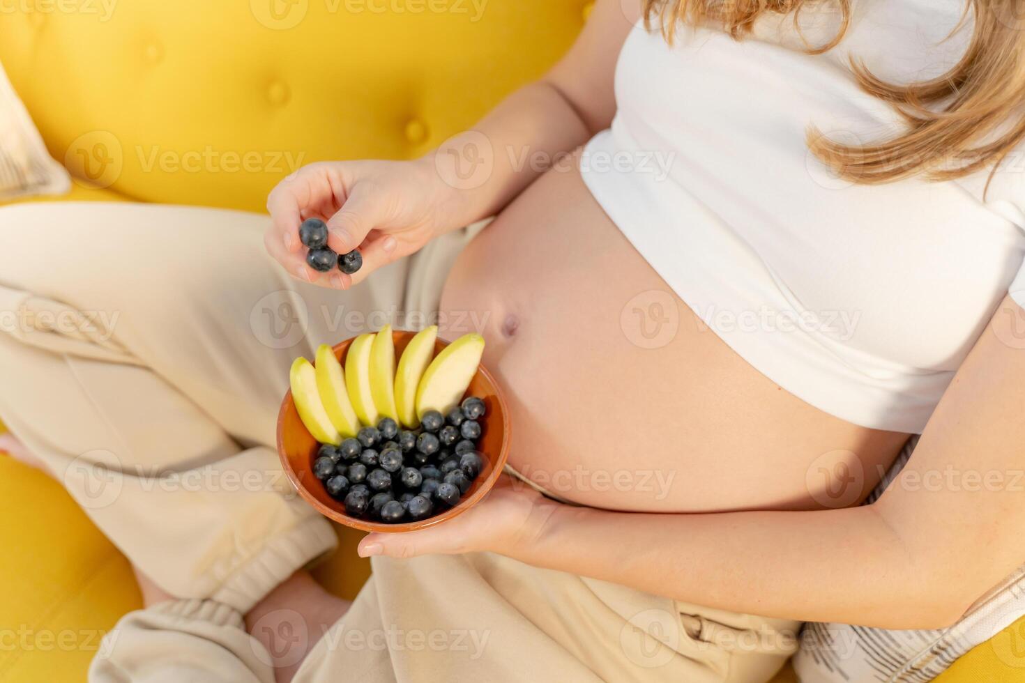 Happy Expecting Mother Enjoying Fresh Blueberries and Apple Slices as a Healthy Snack photo