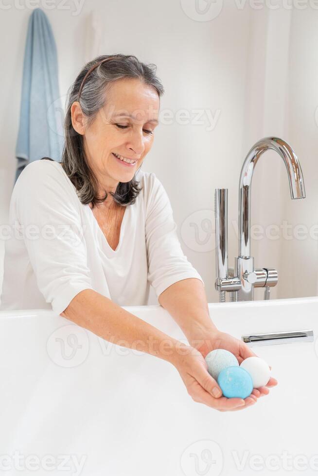 Vertical shot of a happy smiling attractive senior woman morning routine with salt soap aroma balls photo