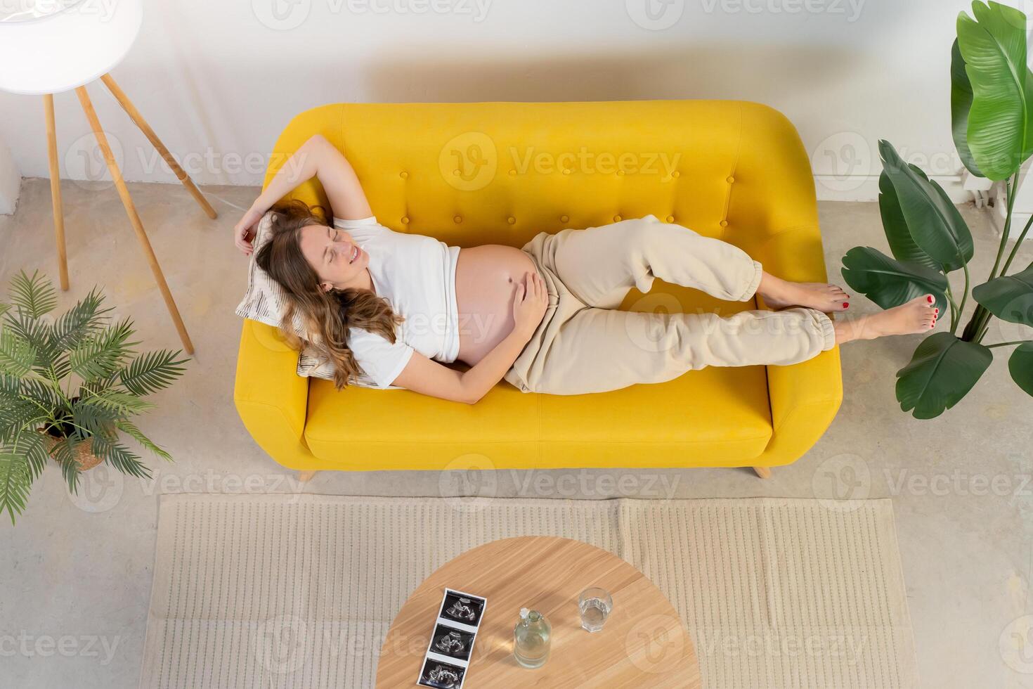 Pregnant woman on yellow sofa photo