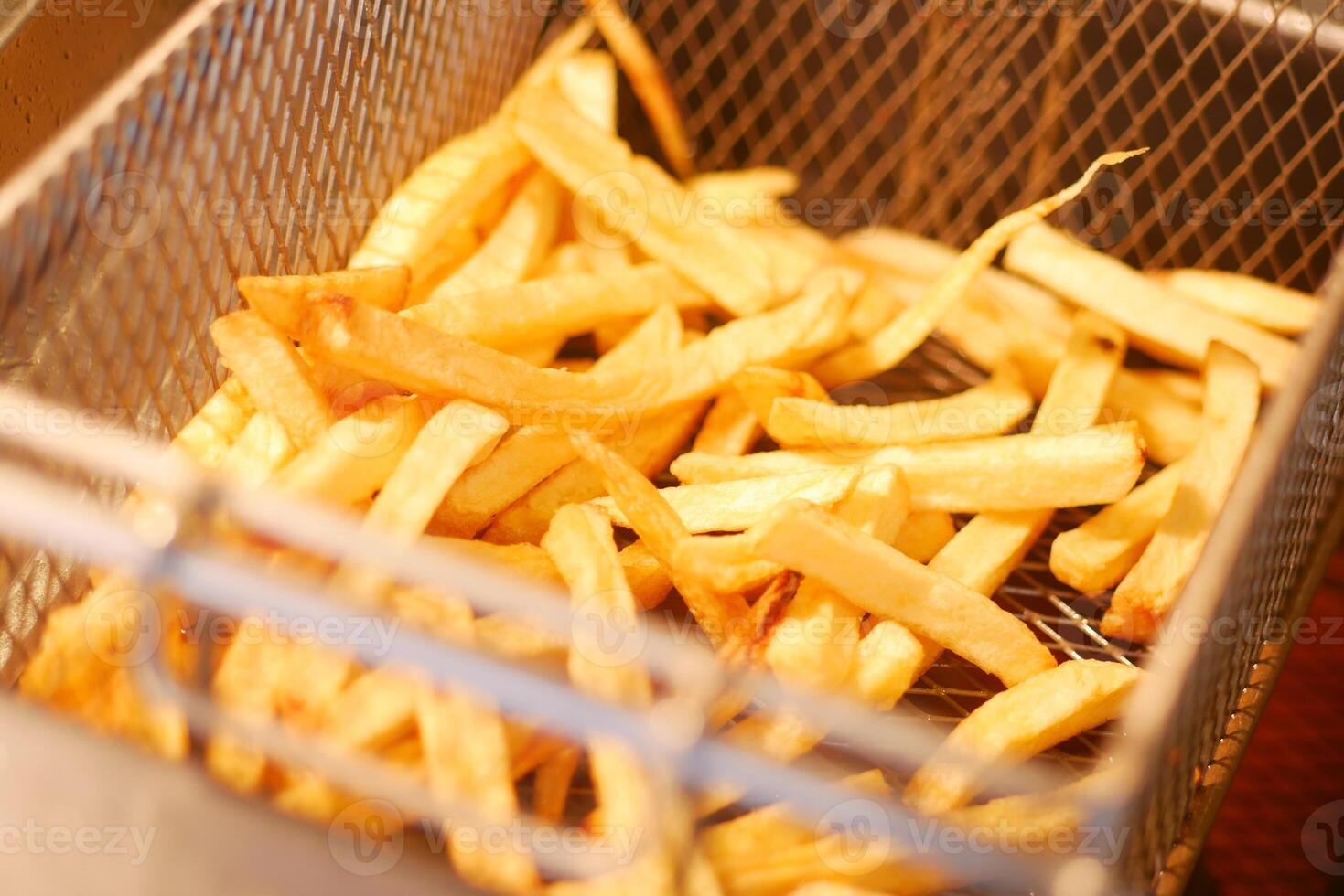 Freshly cooked golden French fries in a frying basket photo