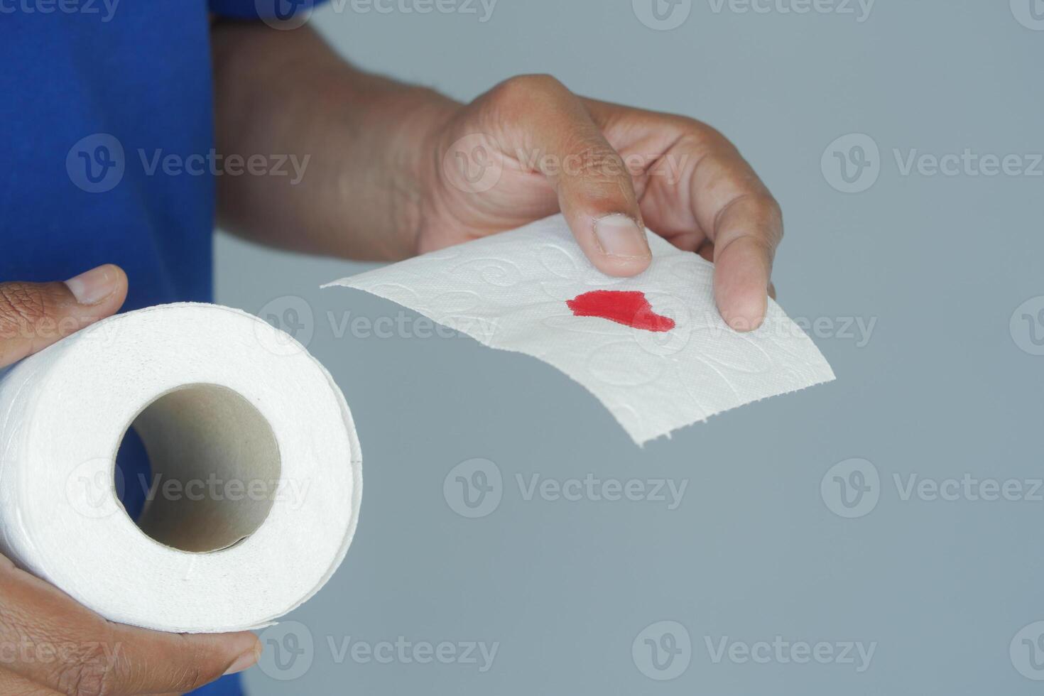 Person holding toilet paper with red stain in close-up photo