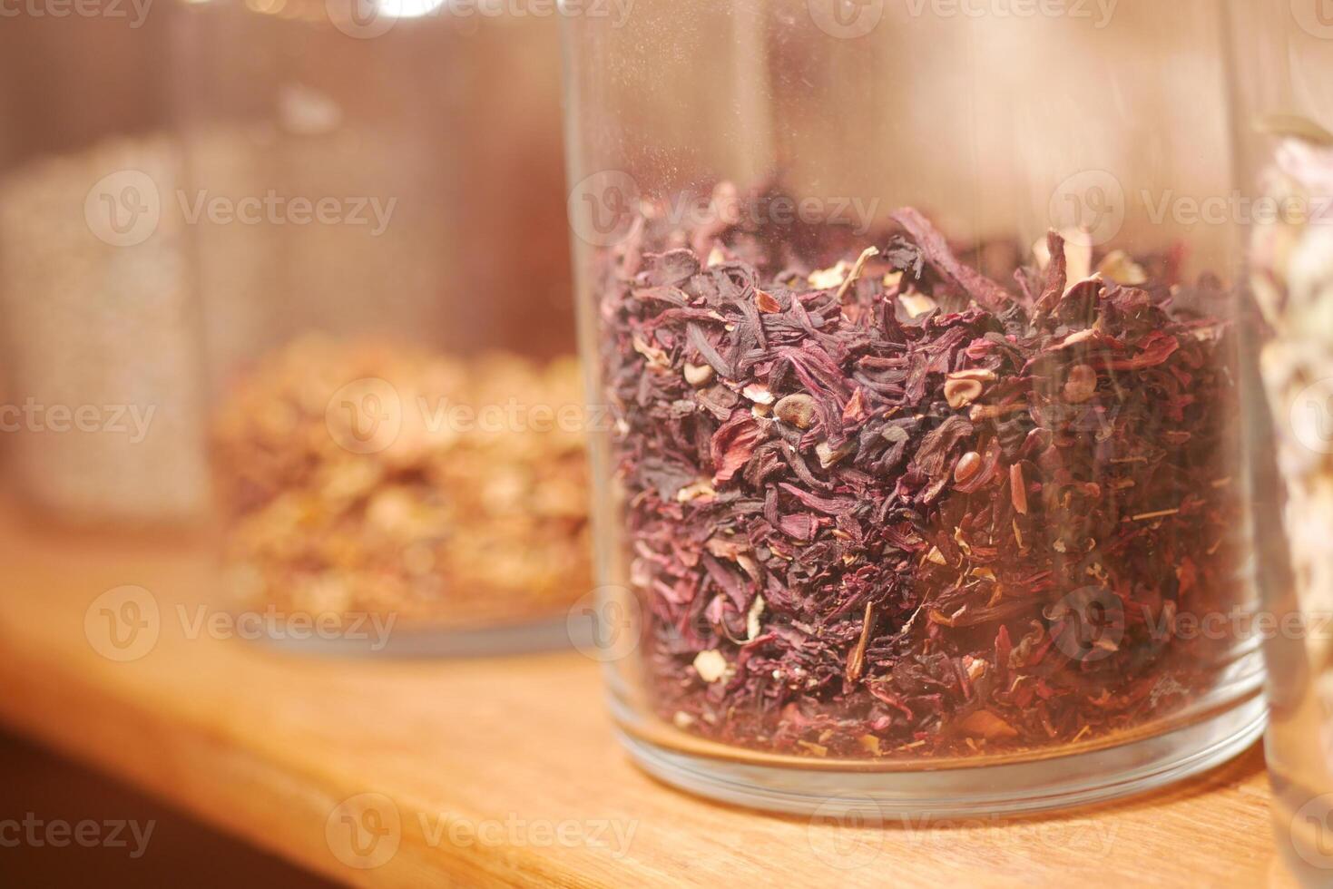 Colorful dried herbs and spices displayed in glass jars photo